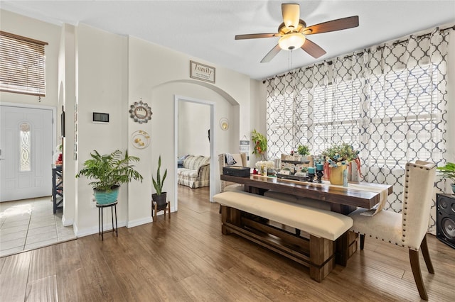 dining area featuring a ceiling fan, arched walkways, and wood finished floors