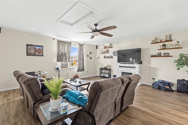 living area featuring a fireplace, wood finished floors, attic access, and baseboards