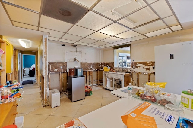 kitchen featuring a paneled ceiling, white cabinetry, light tile patterned floors, and tasteful backsplash