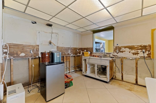 interior space with white cabinets, light tile patterned floors, a paneled ceiling, and sink