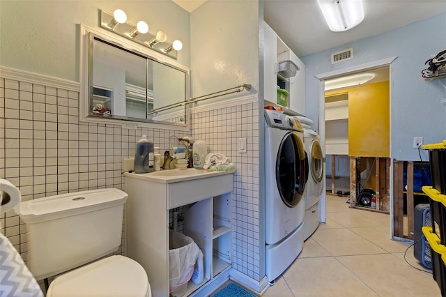 washroom featuring light tile patterned flooring, independent washer and dryer, and tile walls