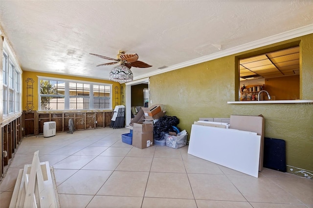 interior space featuring light tile patterned floors, a textured ceiling, ceiling fan, and ornamental molding