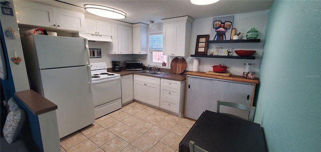 7045 Lenox Dr, New Port Richey, FL 34653 - kitchen featuring white appliances, under cabinet range hood, white cabinets, light tile patterned floors, and dark countertops
