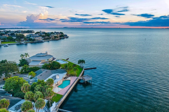 aerial view at dusk featuring a water view