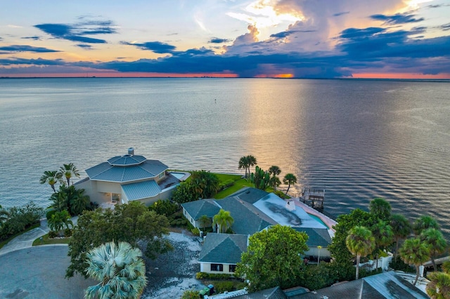 aerial view at dusk featuring a water view