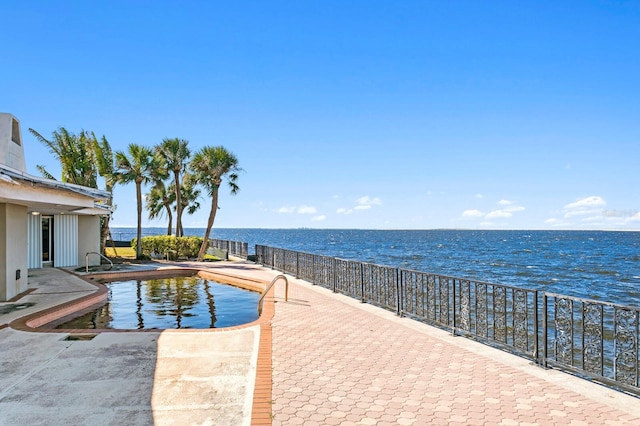 view of swimming pool featuring a patio and a water view