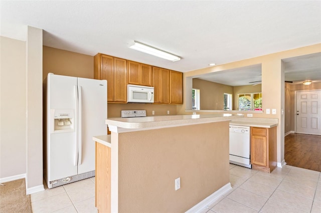 kitchen with a center island, light tile patterned flooring, white appliances, and kitchen peninsula