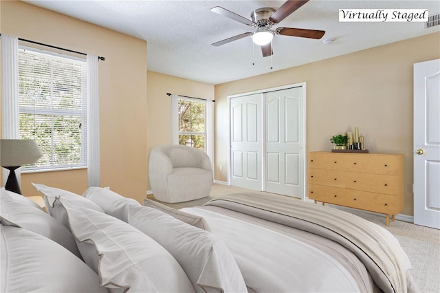 carpeted bedroom featuring ceiling fan, a textured ceiling, and a closet