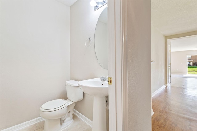 bathroom featuring toilet, a textured ceiling, and hardwood / wood-style flooring