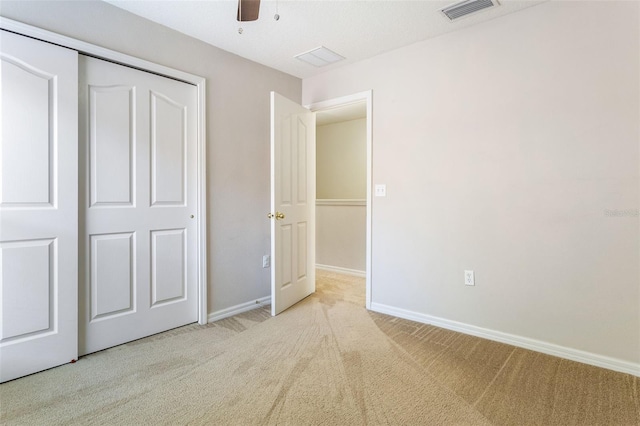 unfurnished bedroom with ceiling fan, light colored carpet, and a closet