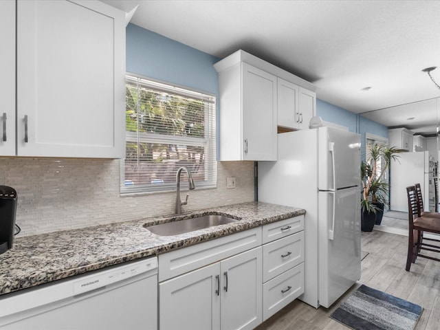 kitchen with white cabinets, white appliances, light stone counters, and sink