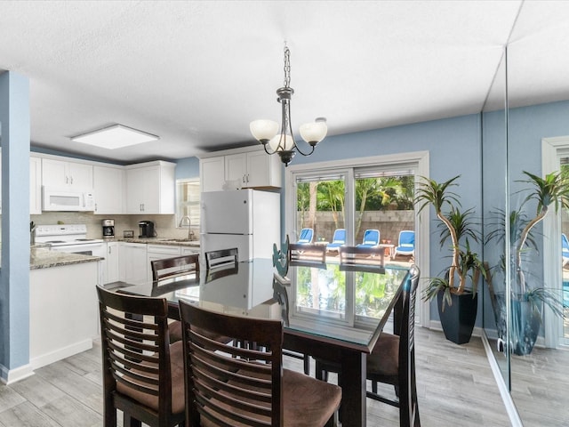 dining area featuring light wood-type flooring, a notable chandelier, and sink