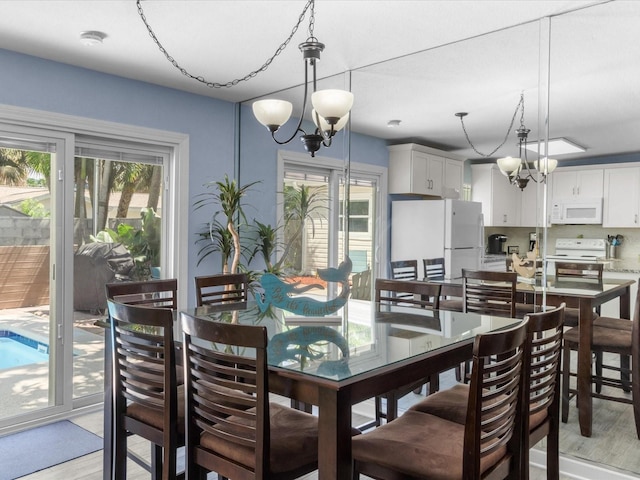 dining space featuring light hardwood / wood-style flooring, a healthy amount of sunlight, and a notable chandelier