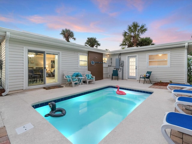 pool at dusk featuring a patio area