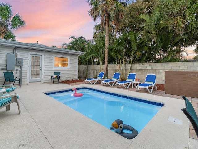 pool at dusk featuring a patio