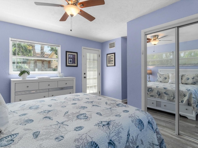 bedroom with ceiling fan, access to exterior, wood-type flooring, and a textured ceiling