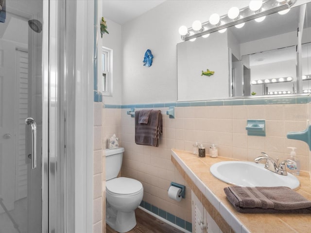 bathroom featuring hardwood / wood-style floors, vanity, a shower with door, toilet, and tile walls