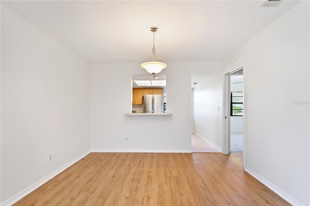 empty room with a textured ceiling and light wood-type flooring