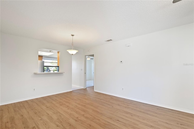 spare room featuring a textured ceiling and light hardwood / wood-style floors