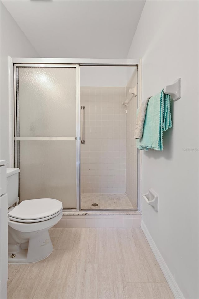 bathroom featuring toilet and a shower with shower door