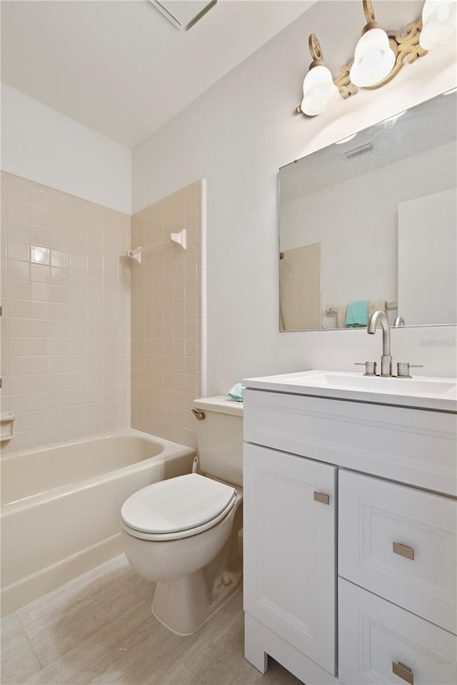 full bathroom featuring hardwood / wood-style floors, tiled shower / bath combo, toilet, and vanity