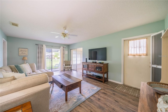 living room featuring ceiling fan, dark wood-type flooring, and a textured ceiling