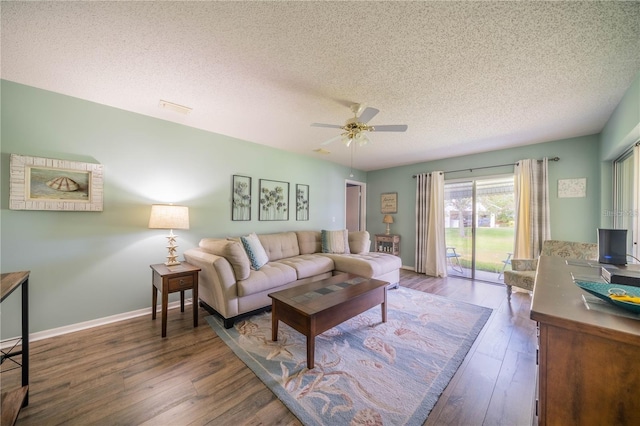 living room featuring ceiling fan, dark hardwood / wood-style flooring, and a textured ceiling