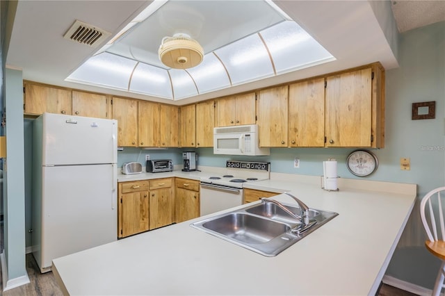 kitchen with kitchen peninsula, white appliances, hardwood / wood-style flooring, and sink