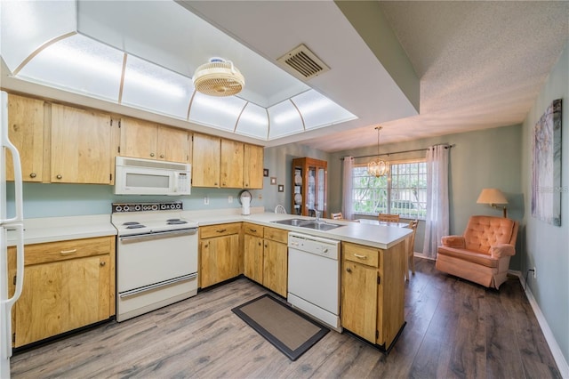 kitchen featuring sink, kitchen peninsula, pendant lighting, white appliances, and wood-type flooring