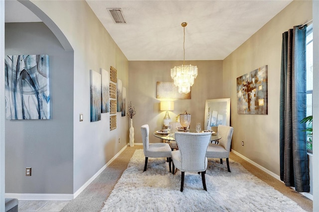 dining area with light carpet and an inviting chandelier