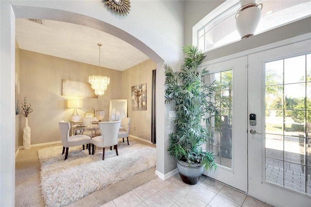 interior space featuring french doors, light tile patterned floors, and a notable chandelier