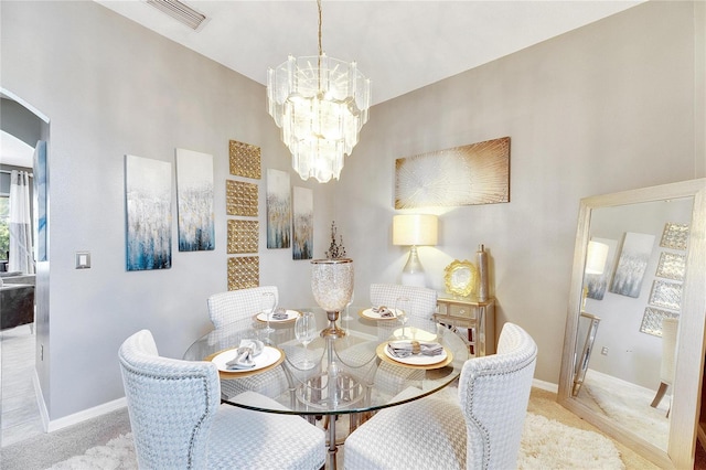 dining area with light carpet and a chandelier