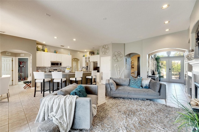 living room with french doors, a textured ceiling, and light tile patterned flooring