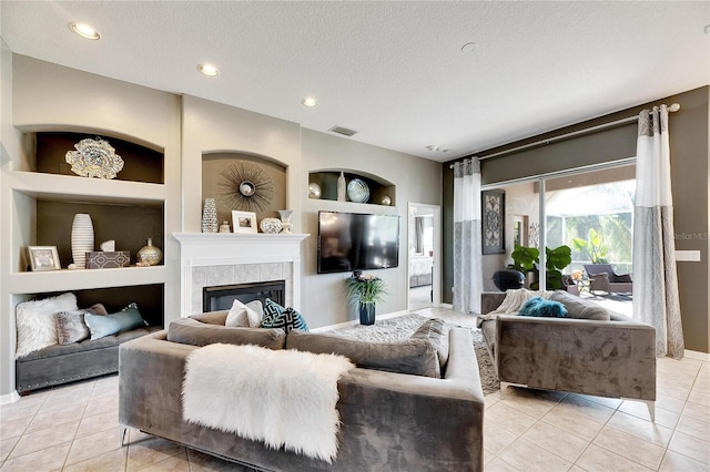 living room with a fireplace, built in shelves, a textured ceiling, and light tile patterned flooring