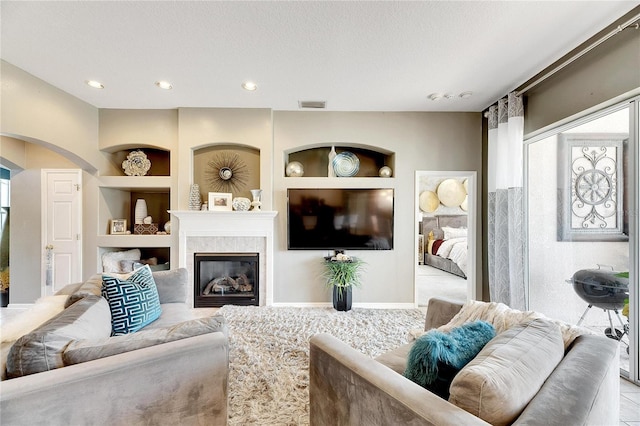 living room featuring a fireplace, built in features, and a textured ceiling