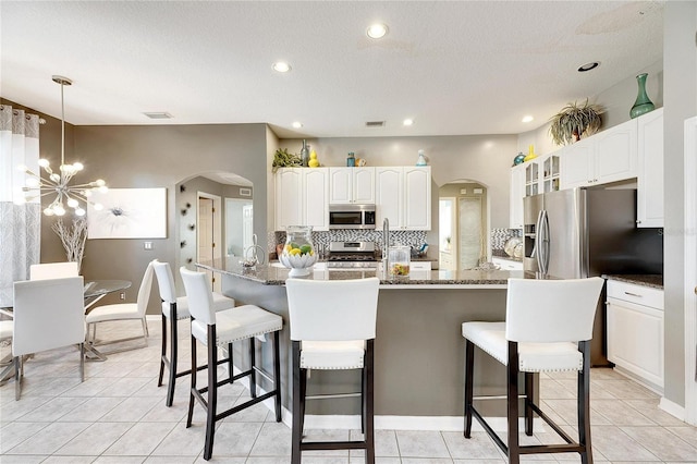 kitchen with white cabinets, a kitchen breakfast bar, dark stone countertops, and appliances with stainless steel finishes