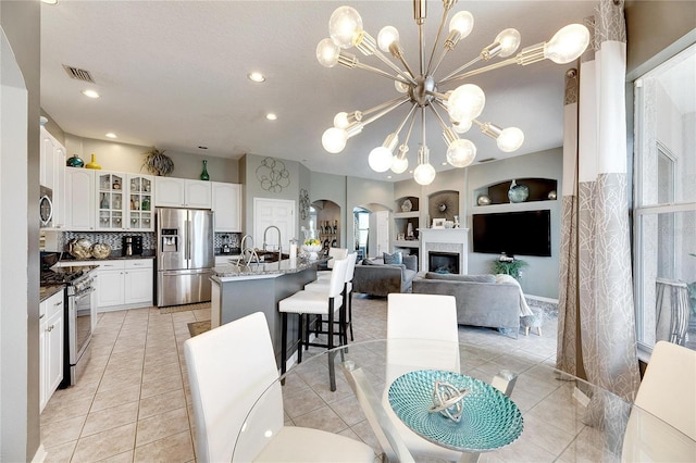 dining area with a notable chandelier, light tile patterned floors, sink, and built in shelves