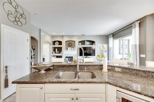 kitchen featuring a textured ceiling, white cabinetry, dark stone countertops, and sink