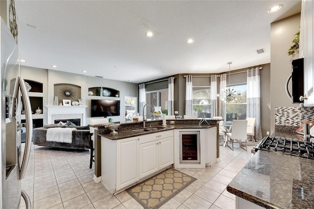 kitchen with stainless steel appliances, sink, decorative light fixtures, white cabinetry, and wine cooler