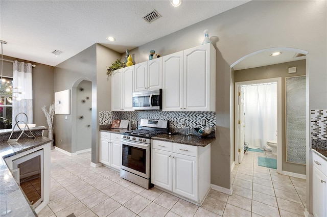 kitchen featuring dark stone countertops, white cabinetry, a textured ceiling, and appliances with stainless steel finishes