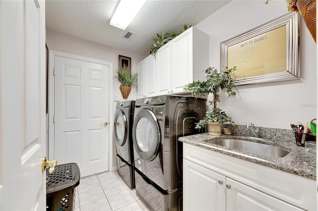 washroom featuring cabinets, a textured ceiling, sink, light tile patterned floors, and separate washer and dryer