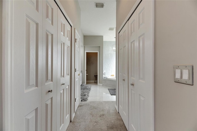 corridor featuring a textured ceiling and light carpet