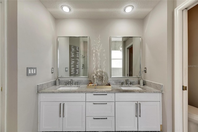 bathroom featuring vanity, a textured ceiling, and toilet