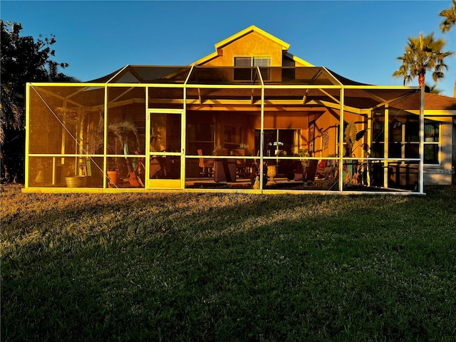 back of house with glass enclosure and a lawn