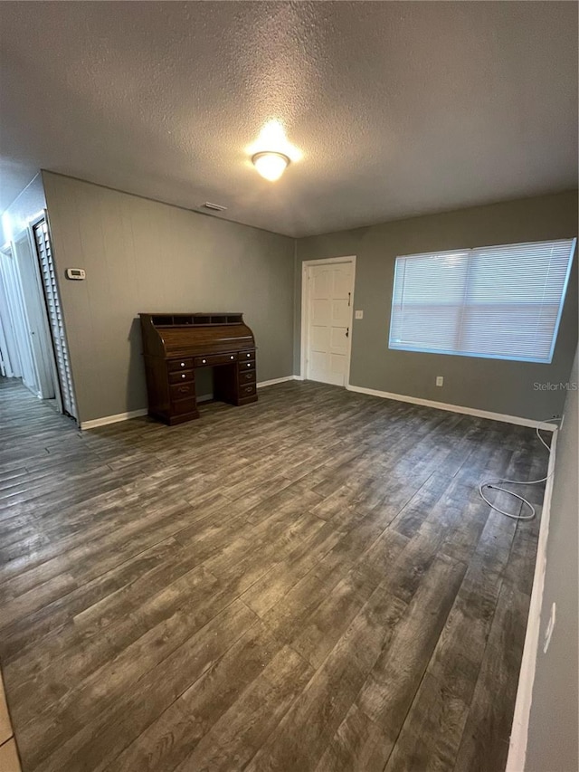 unfurnished living room with dark hardwood / wood-style floors and a textured ceiling