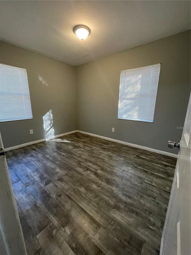 spare room with a textured ceiling and dark hardwood / wood-style flooring