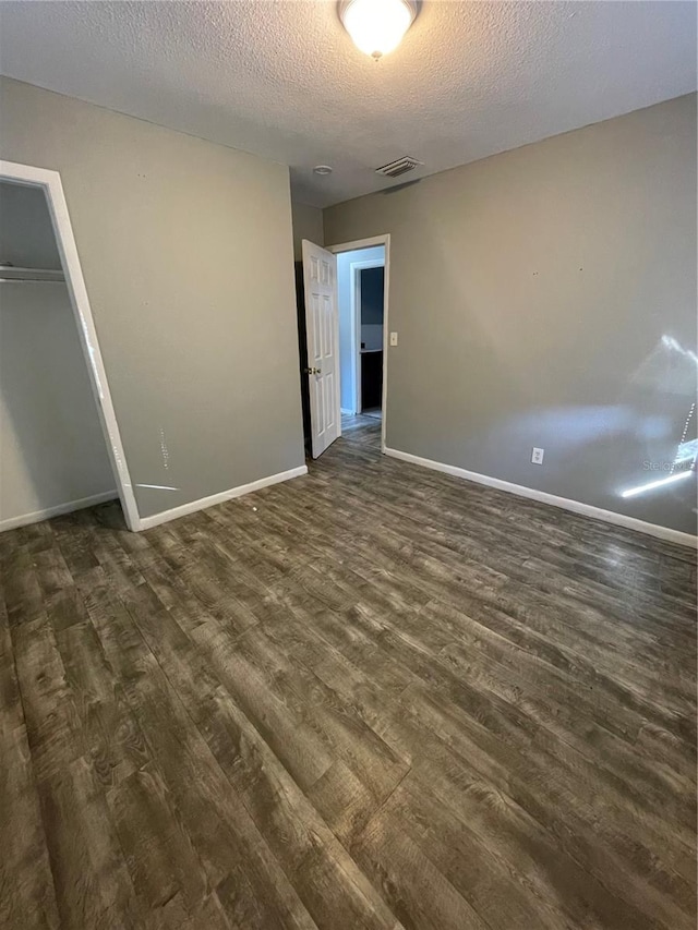 unfurnished bedroom featuring dark hardwood / wood-style flooring, a closet, and a textured ceiling