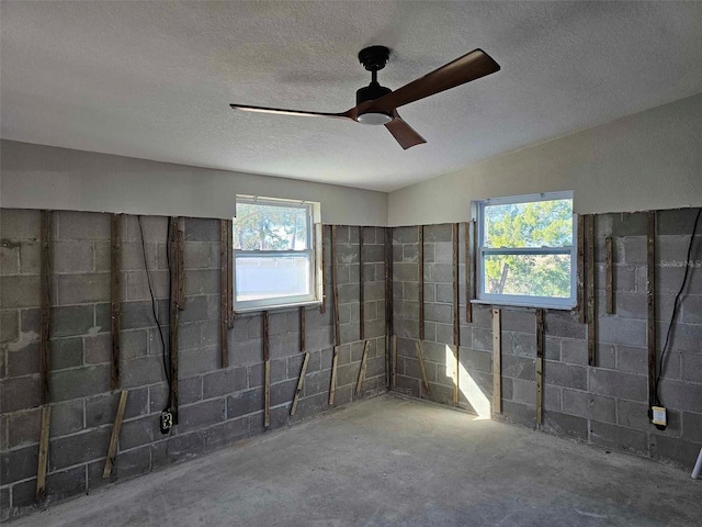 basement featuring ceiling fan and a textured ceiling