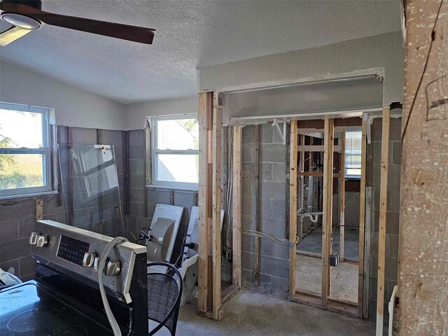 misc room featuring concrete flooring, a textured ceiling, vaulted ceiling, and ceiling fan