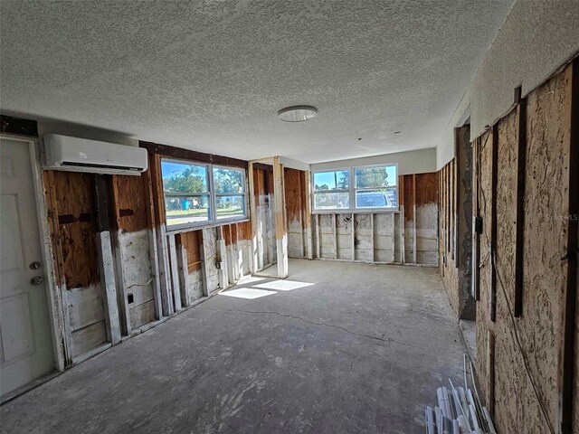 miscellaneous room with a wall mounted air conditioner, a textured ceiling, and plenty of natural light